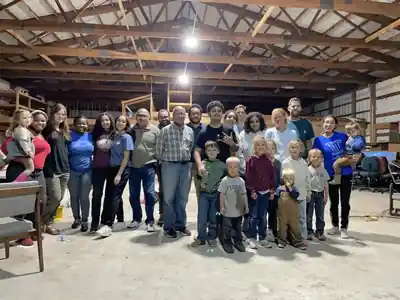 A large group of adults and children standing in the shop under work lights