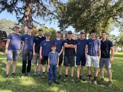 A group of volunteers on the lawn in front of the brick campus